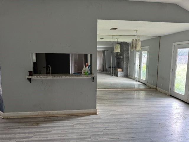 unfurnished living room featuring lofted ceiling, wood finished floors, visible vents, baseboards, and a fireplace
