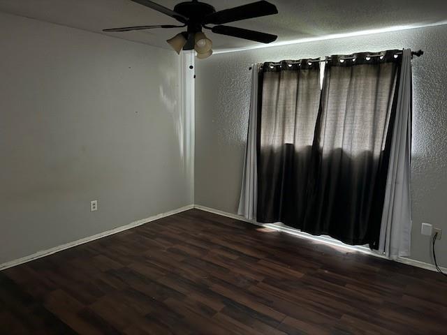 unfurnished room featuring baseboards, wood finished floors, and ceiling fan