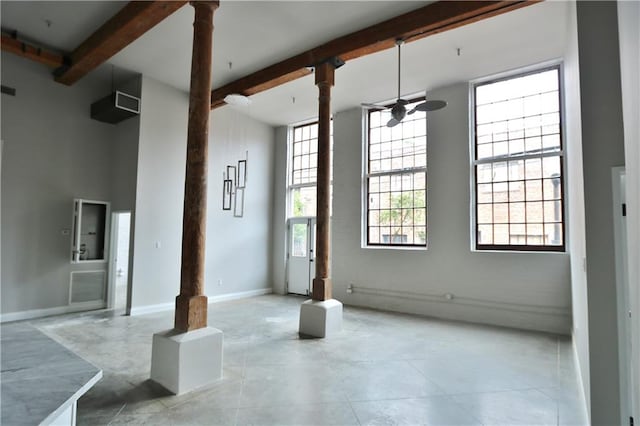 interior space featuring a towering ceiling, plenty of natural light, beam ceiling, and tile patterned flooring