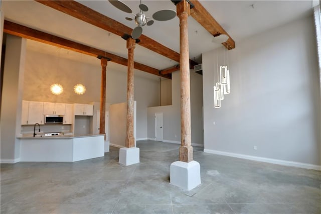 unfurnished living room with a chandelier, beam ceiling, concrete floors, and a towering ceiling