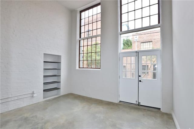 interior space with a healthy amount of sunlight, a high ceiling, and french doors