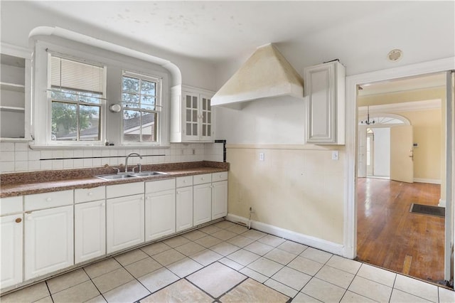 442527 Music St, New Orleans, LA 70122 - kitchen featuring a sink, decorative backsplash, white cabinets, light tile patterned floors, and glass insert cabinets