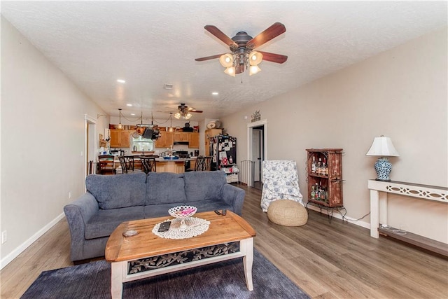 living room with a textured ceiling, ceiling fan, and hardwood / wood-style floors