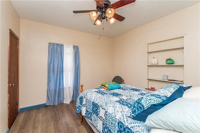 bedroom with a textured ceiling, wood-type flooring, and ceiling fan