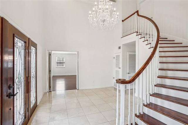 entrance foyer with light tile patterned floors, a towering ceiling, and a chandelier