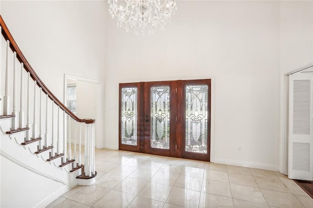 entryway with a high ceiling, light tile patterned flooring, and a notable chandelier