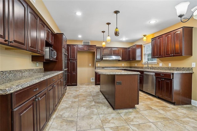 kitchen featuring light stone counters, pendant lighting, sink, appliances with stainless steel finishes, and a center island