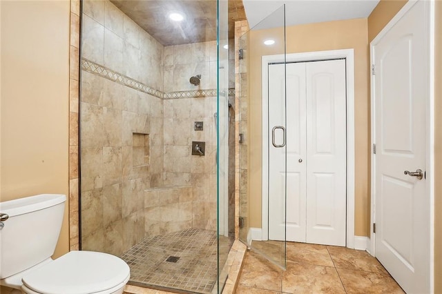 bathroom with tile patterned flooring, toilet, and a shower with door