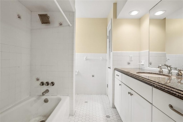 bathroom with tile walls, vanity, tiled shower / bath combo, and tile patterned floors