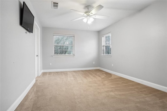 carpeted spare room featuring ceiling fan and plenty of natural light