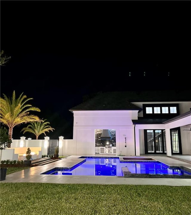 pool at night with a lawn and a patio