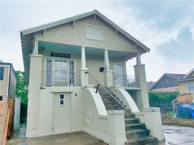 bungalow-style house featuring a porch, stairway, and fence