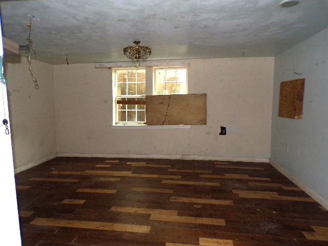 spare room featuring a textured ceiling and dark hardwood / wood-style floors