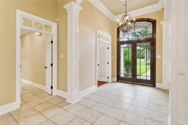 entrance foyer with crown molding, a chandelier, light tile patterned floors, and decorative columns