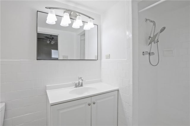 bathroom with tile walls, ceiling fan, a shower, and vanity