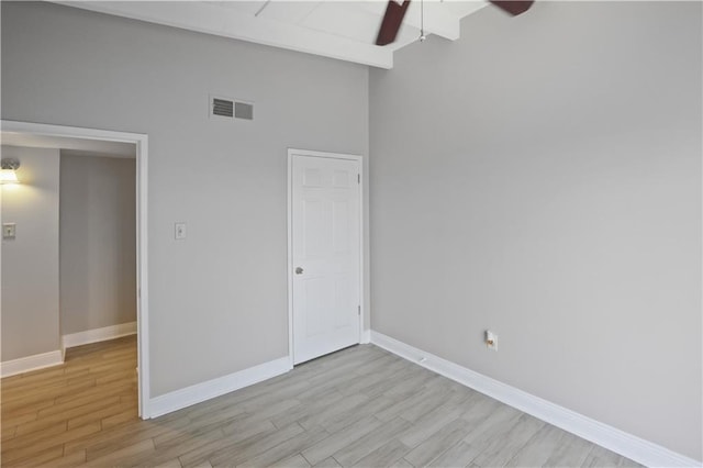 unfurnished bedroom featuring ceiling fan, beamed ceiling, light hardwood / wood-style flooring, and high vaulted ceiling