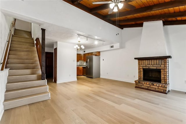 unfurnished living room featuring a fireplace, wood ceiling, ceiling fan with notable chandelier, and light wood-type flooring