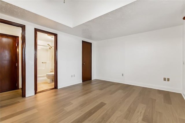 unfurnished bedroom with hardwood / wood-style floors and ensuite bath