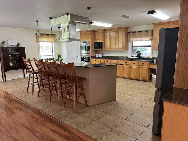 kitchen featuring a kitchen bar, light hardwood / wood-style flooring, black appliances, pendant lighting, and a kitchen island