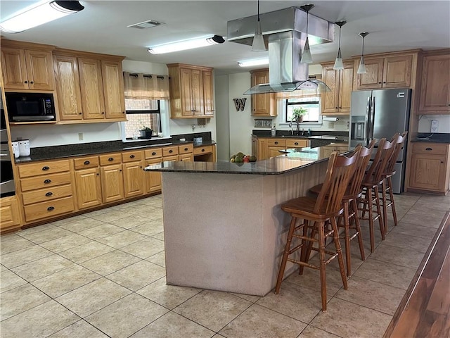 kitchen featuring a kitchen breakfast bar, pendant lighting, light tile patterned floors, a center island, and stainless steel appliances