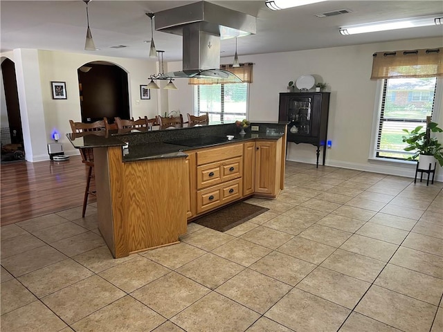 kitchen with light wood-type flooring, island exhaust hood, black electric stovetop, a kitchen bar, and pendant lighting