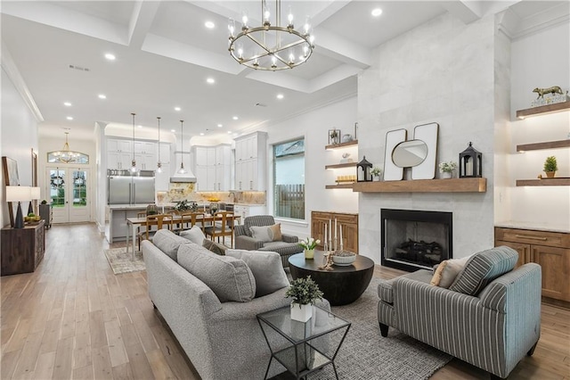 living room with a healthy amount of sunlight, light wood-type flooring, a notable chandelier, and a large fireplace