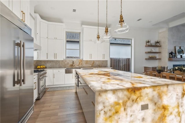 kitchen featuring a center island, light hardwood / wood-style floors, white cabinetry, sink, and premium appliances