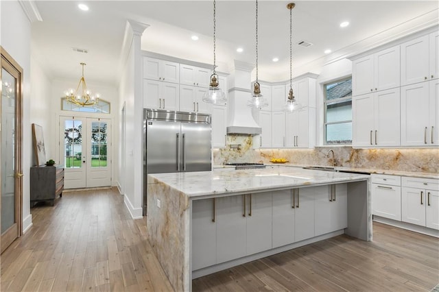 kitchen featuring pendant lighting, a kitchen island, white cabinets, and light hardwood / wood-style floors