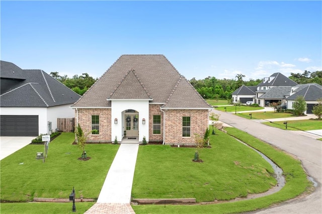 french country home featuring a garage and a front yard