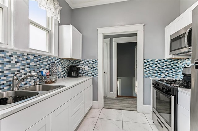 kitchen with sink, appliances with stainless steel finishes, white cabinetry, and tasteful backsplash