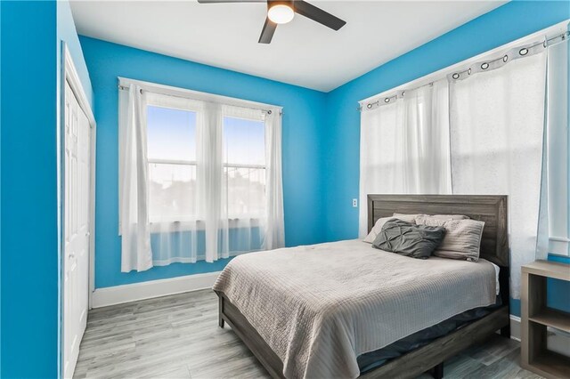 bedroom with light hardwood / wood-style flooring, ceiling fan, and a closet