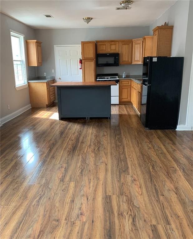 kitchen featuring black appliances, a kitchen island, and dark hardwood / wood-style flooring