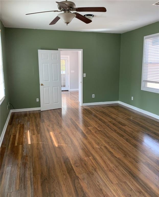 spare room with a healthy amount of sunlight, dark hardwood / wood-style floors, and ceiling fan