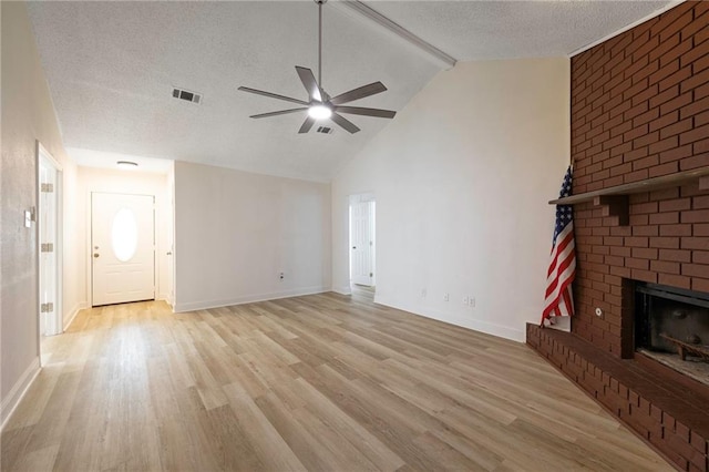 unfurnished living room featuring a brick fireplace, light hardwood / wood-style floors, ceiling fan, high vaulted ceiling, and a textured ceiling