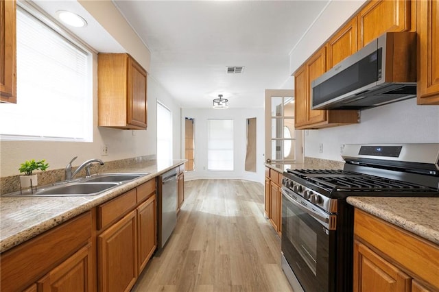 kitchen featuring light hardwood / wood-style flooring, light stone counters, stainless steel appliances, and sink