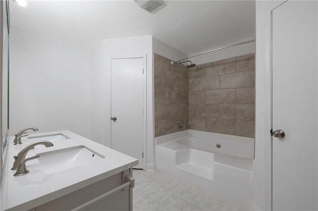 bathroom featuring tiled shower / bath combo, a textured ceiling, and vanity