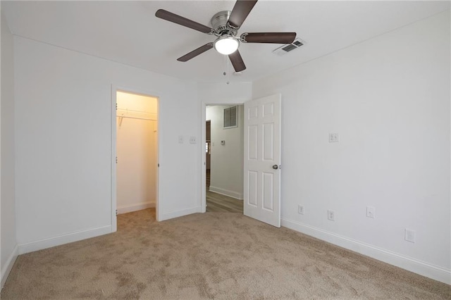 unfurnished bedroom featuring light colored carpet, a spacious closet, ceiling fan, and a closet