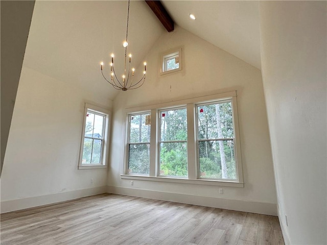 unfurnished room with beamed ceiling, plenty of natural light, an inviting chandelier, and light hardwood / wood-style floors