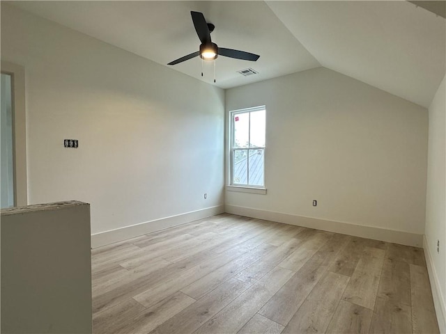 empty room with ceiling fan, vaulted ceiling, and light hardwood / wood-style floors