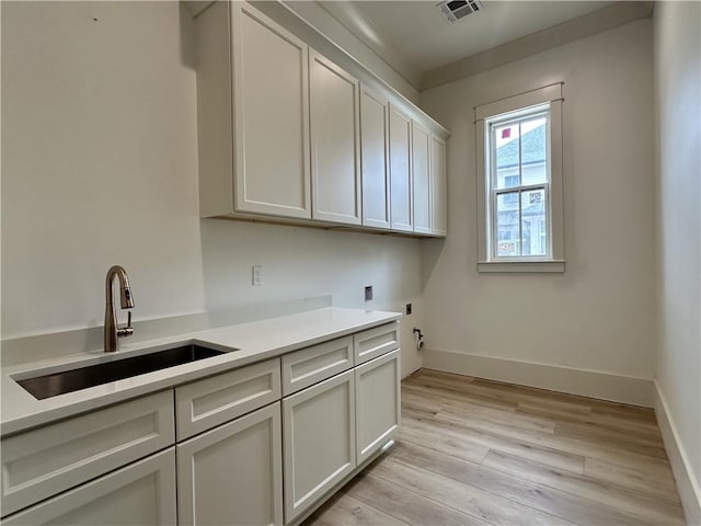 laundry area with light wood-type flooring, sink, electric dryer hookup, washer hookup, and cabinets