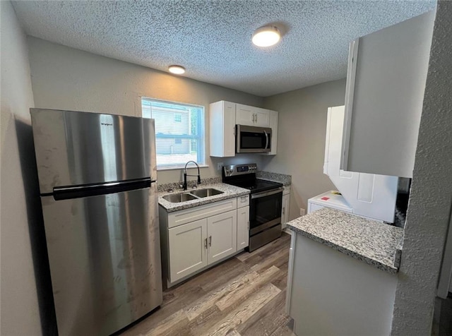 kitchen featuring appliances with stainless steel finishes, light wood-type flooring, white cabinetry, and sink