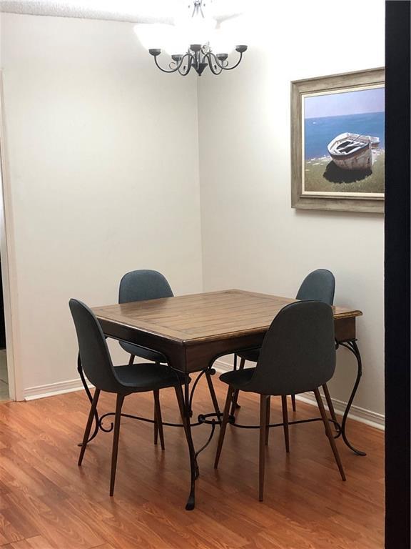 dining area with a notable chandelier, light wood-style flooring, and baseboards