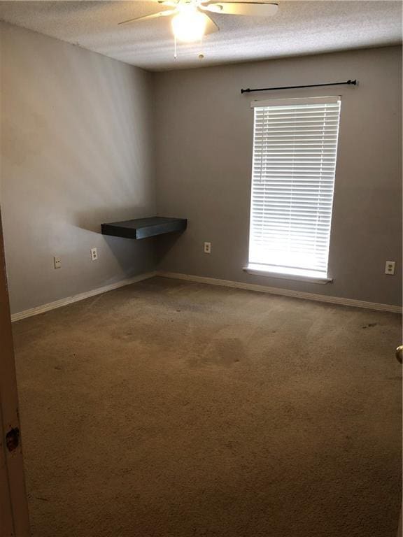 unfurnished room with a textured ceiling, baseboards, and carpet flooring