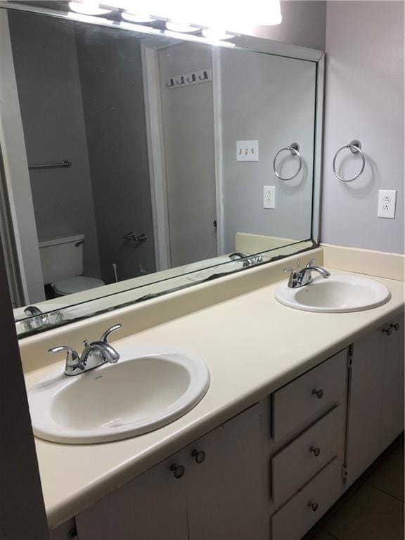 bathroom featuring tile patterned floors, a sink, toilet, and double vanity