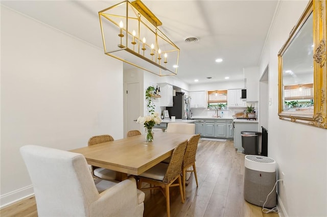 dining area with crown molding, light hardwood / wood-style flooring, and sink