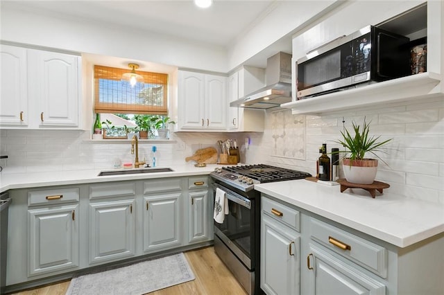 kitchen featuring gray cabinets, tasteful backsplash, stainless steel appliances, sink, and wall chimney range hood