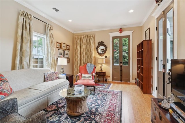 living room featuring light hardwood / wood-style floors, crown molding, and french doors