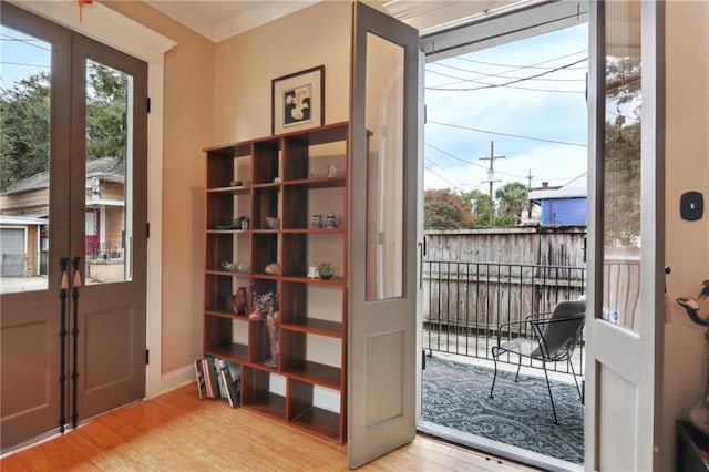 doorway to outside featuring light hardwood / wood-style floors and crown molding