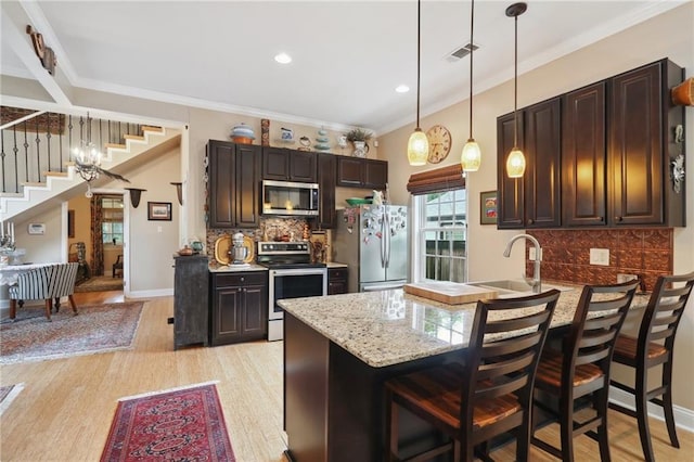 kitchen with appliances with stainless steel finishes, tasteful backsplash, a breakfast bar area, and light hardwood / wood-style floors