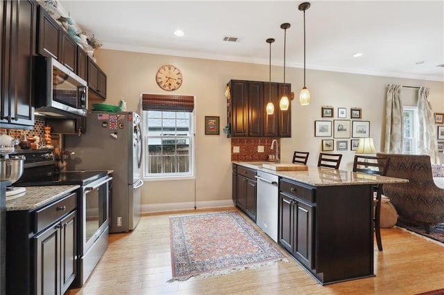 kitchen featuring light hardwood / wood-style flooring, a kitchen bar, stainless steel appliances, backsplash, and light stone counters